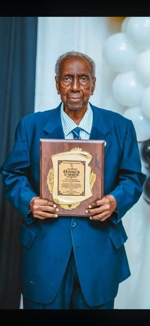 Me Antoine Norgaisse tenant une plaque d’honneur et mérite
